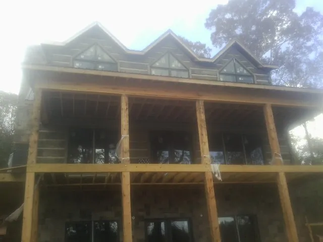 Dormers and porch framing on a large log home under construction — Roof Coating work by our crew in North Windham