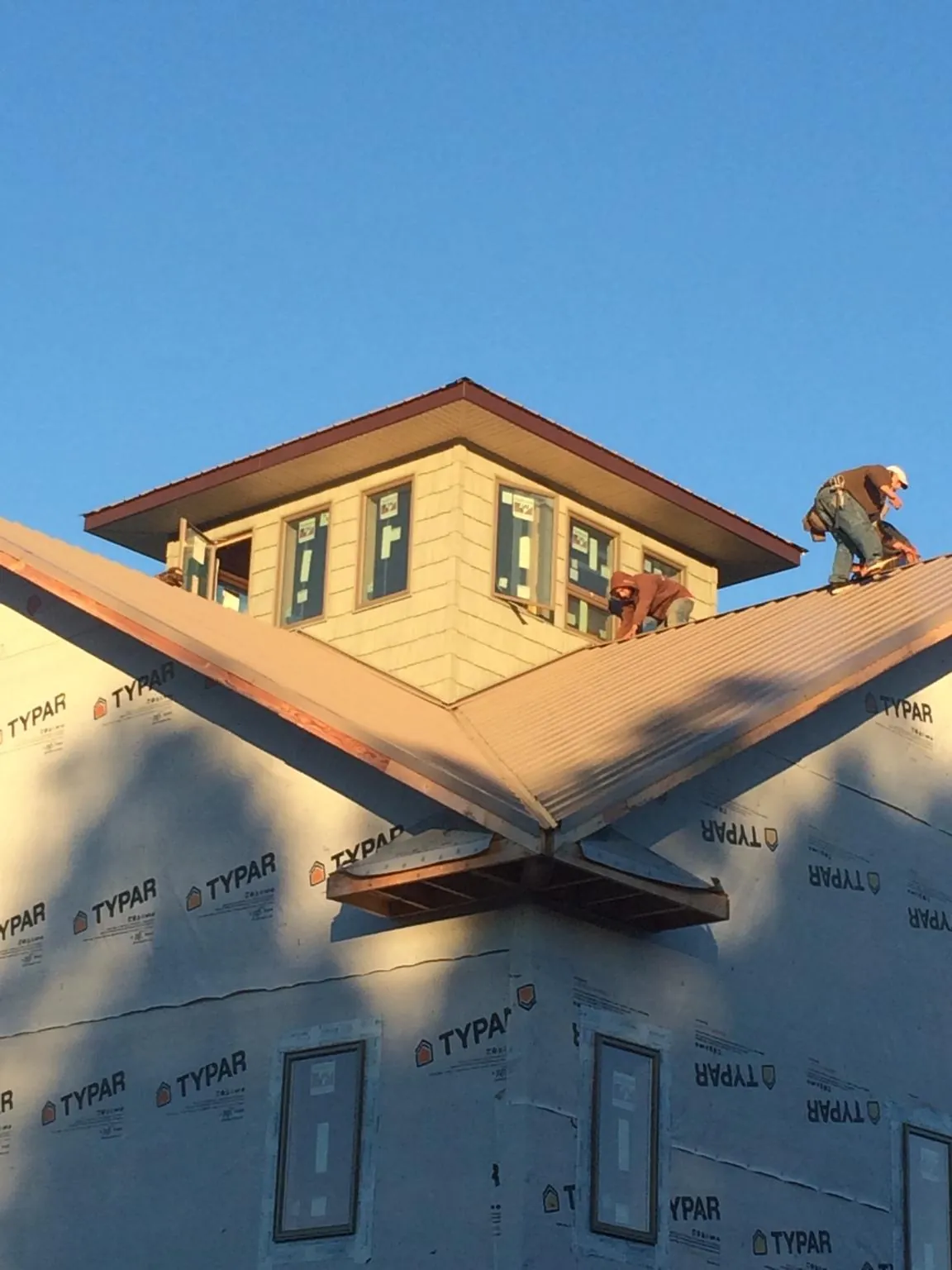 Roofers working around a rooftop cupola on a new metal roof at sunset — Roof Waterproofing in North Windham by Roofing Brothers